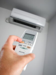 ductless-air-handler-on-wall-with-hand-holding-remote-in-the-foreground